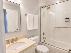 Une salle de bain équipée d’un lavabo, de toilettes et d’une douche à parois de verre.
