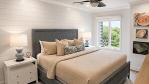 Una camera da letto con un letto, comodini, una ventola a soffitto e una finestra vista.