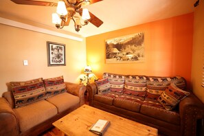 A living room with a sofa, a coffee table, a lamp, and a ceiling fan. - Eagles Nest Cabin, full kitchen, cover carport, Restmore Inn, Hill City (Hill City)