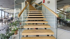 A staircase with wooden steps and glass railings, leading to an upper level. - Cela Hotel (Durrës)