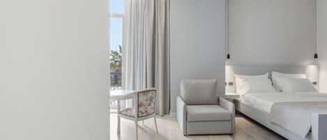 A modern hotel room with a large bed, a chair, a nightstand, and a view of the outdoors.