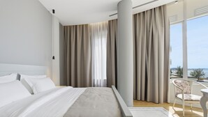 A modern hotel room with a large bed, a view of the sea, and a balcony with a chair. - Cela Hotel (Durrës)