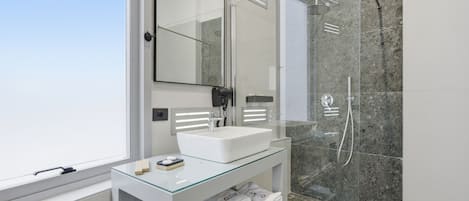Ein modernes Badezimmer mit einer Duschkabine, einem weißen Waschbecken und einem großen Spiegel.