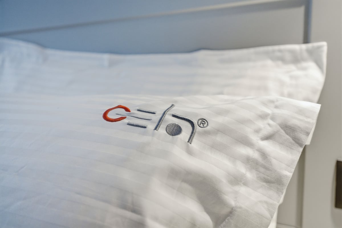 Almohada blanca con un logotipo sobre la cama.