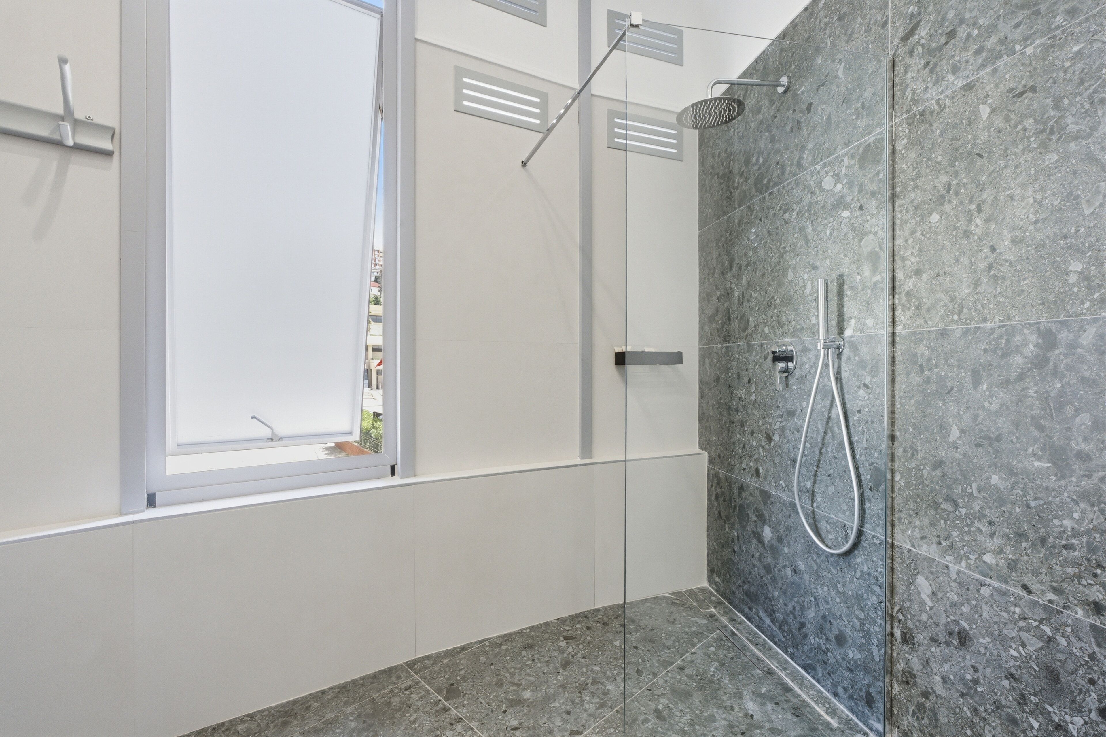 A modern bathroom with a shower, a window, and a view of the outside.