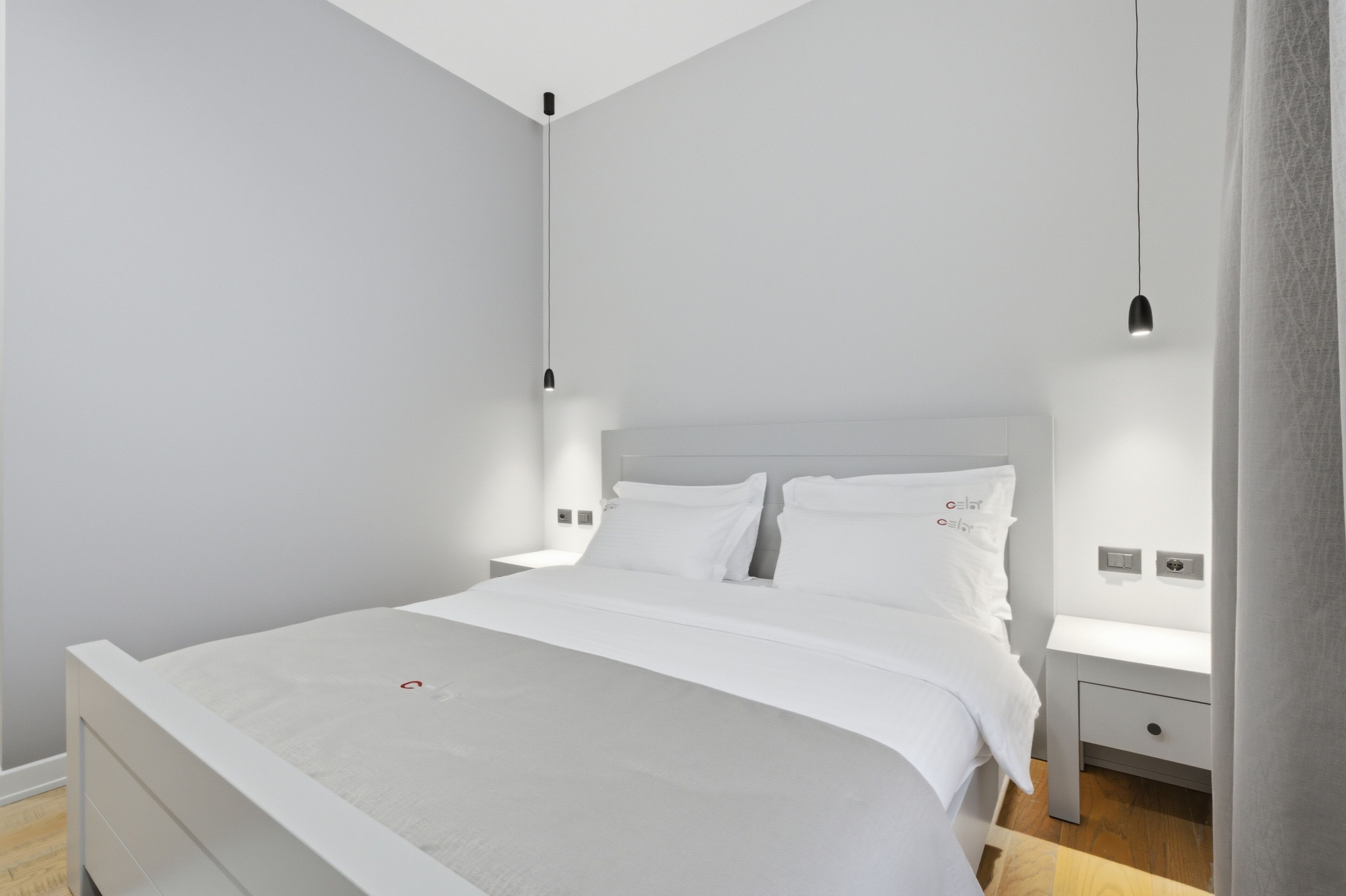 Une chambre à coucher moderne avec un lit, des tables de chevet et des lampes suspendues.