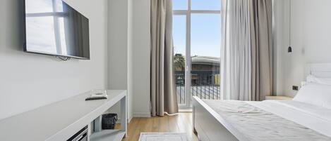 Una habitación de hotel moderna con televisión de pantalla plana, una cama, un escritorio y una ventana con cortinas.