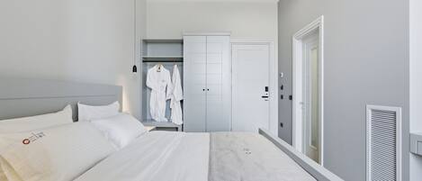 A modern hotel room with a large bed, a wardrobe, and a walk-in closet.