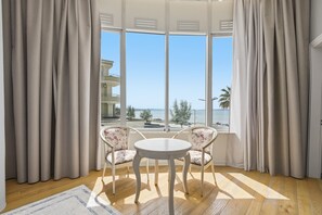 A room with a large window, two chairs, a round table, and a wooden floor. - Cela Hotel (Durrës)
