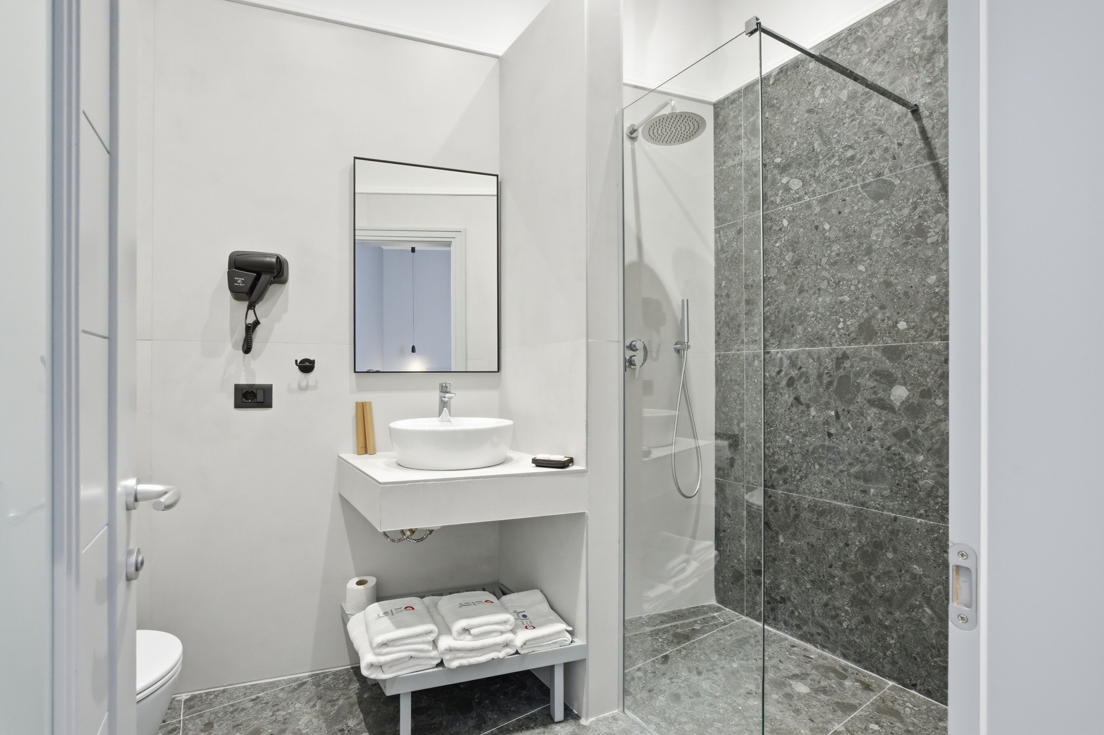 A modern bathroom with a white sink, mirror, and a shower with a glass door.