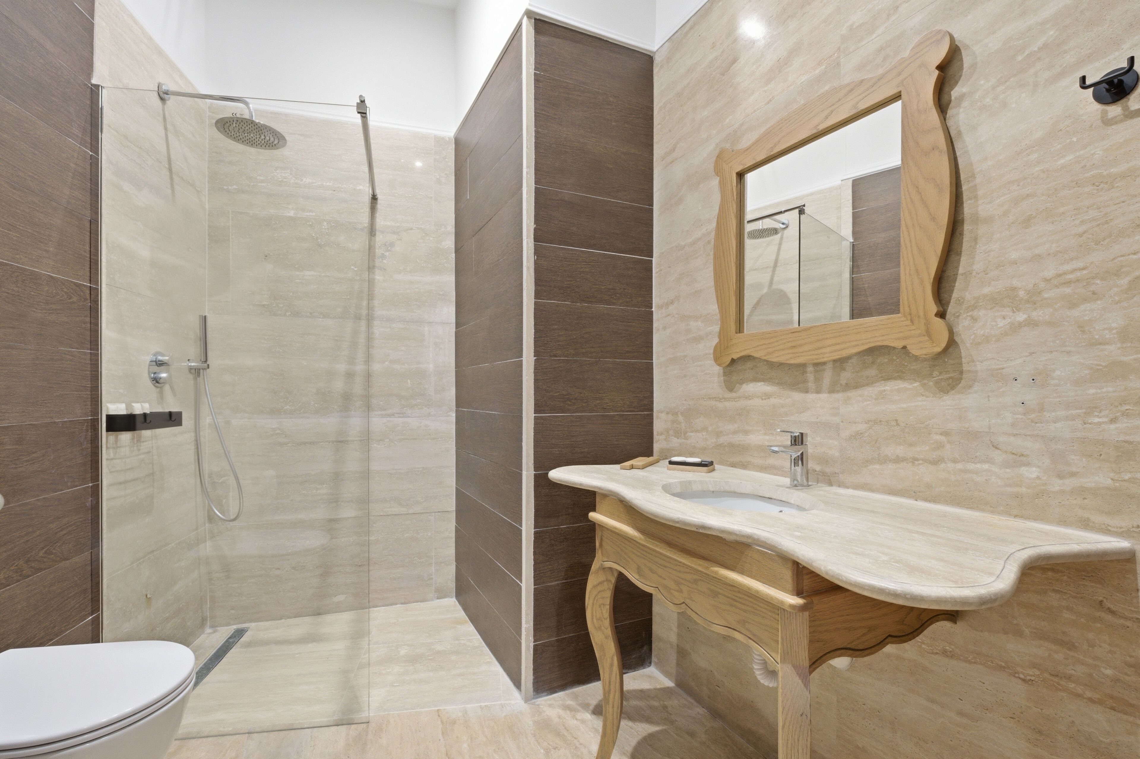 Et moderne badeværelse med brusebad, toilet, håndvask og spejl.