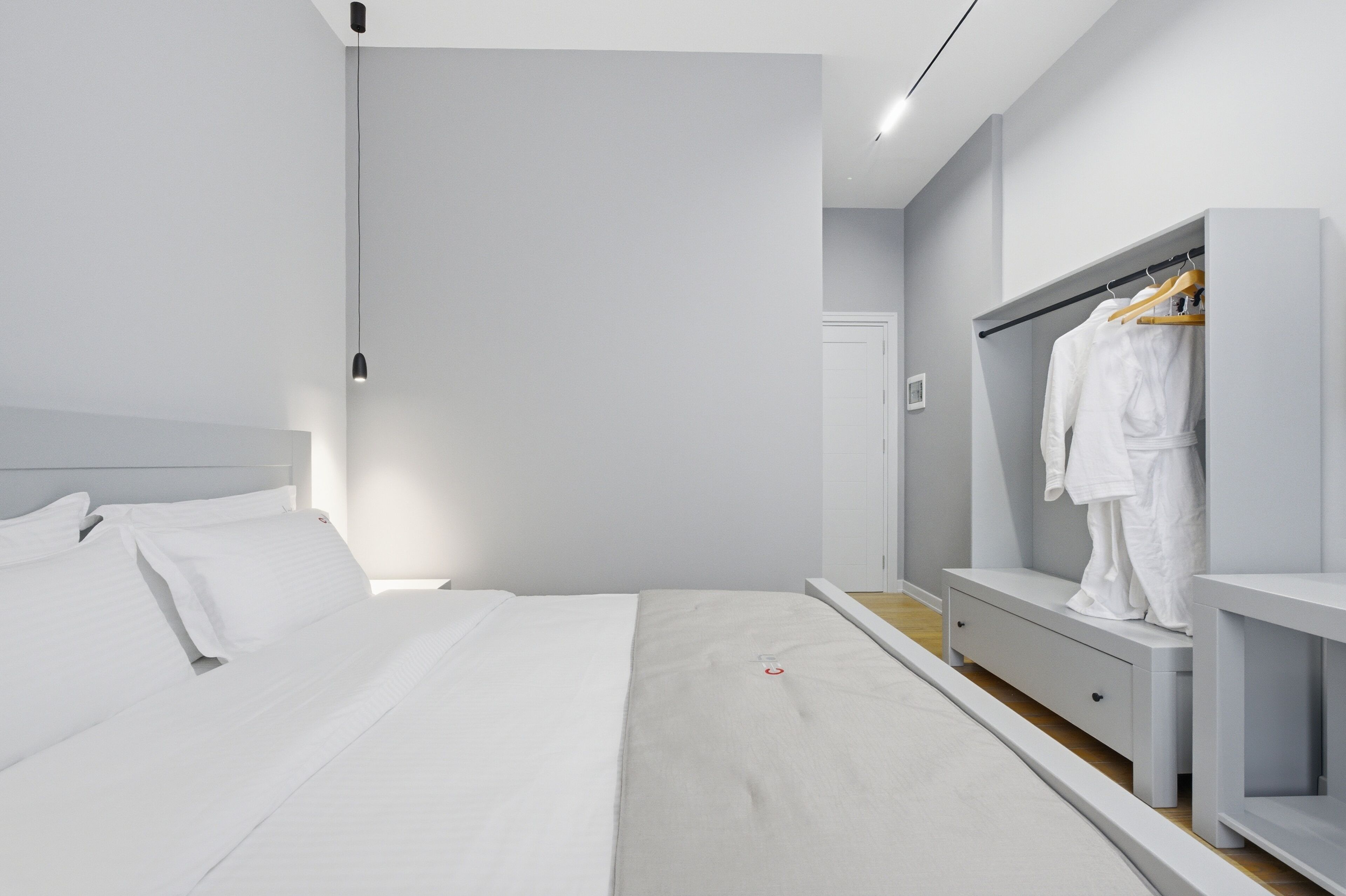 Une chambre moderne comprenant un lit, une table de chevet, une armoire et un luminaire suspendu.