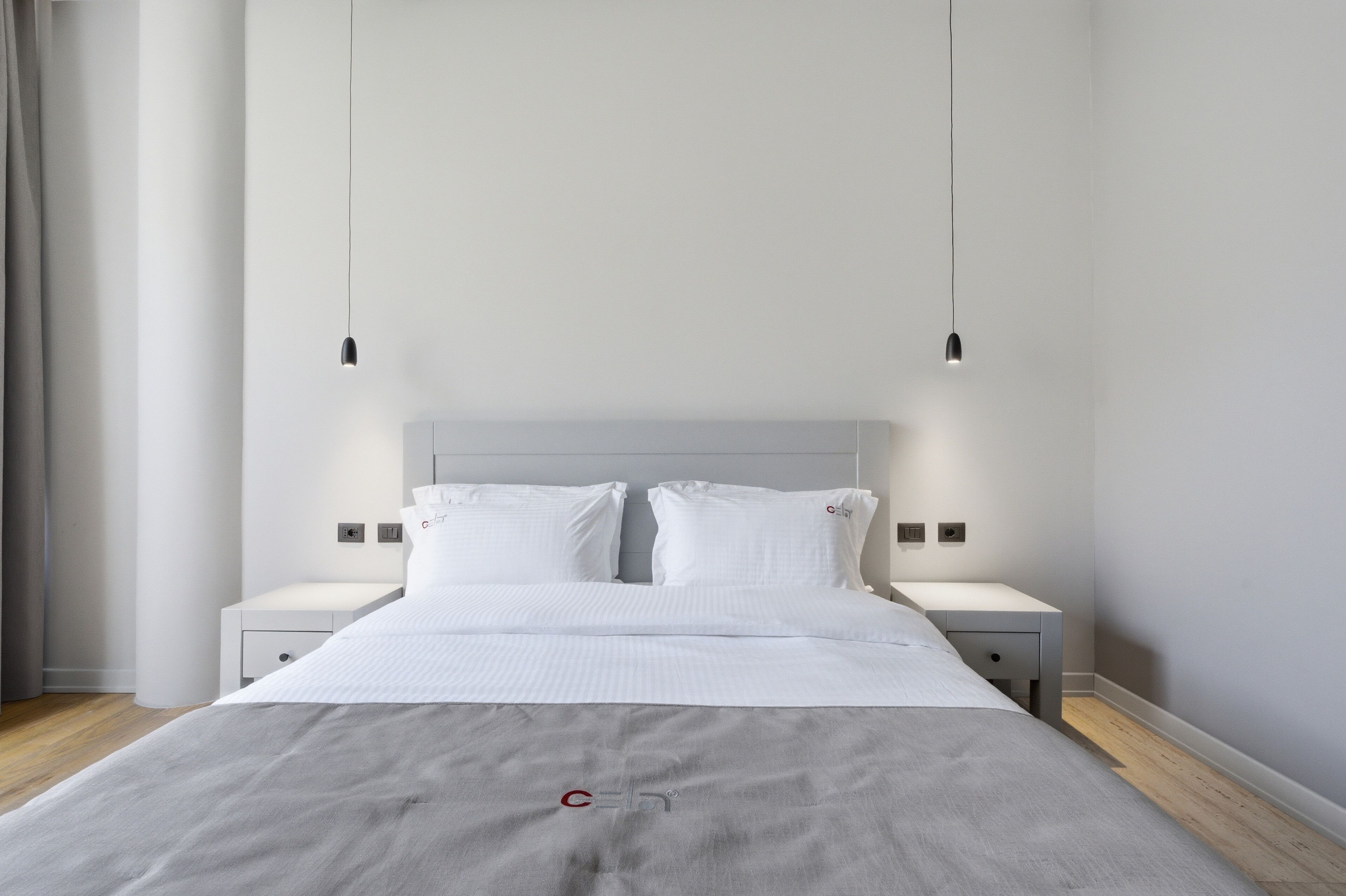 Une chambre à coucher moderne avec un grand lit, deux tables de chevet et une tête de lit.