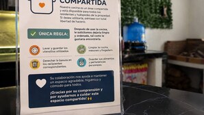 Un cartel detalla las normas de la cocina compartida, como limpiar los utensilios, desechar la basura y guardar alimentos y objetos personales.