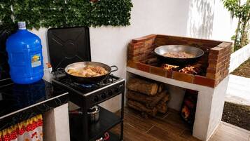 A kitchen with a gas stove, a brick oven, and a blue water jug.