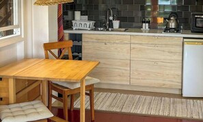Une cuisine compacte avec une table et des chaises en bois, un petit évier et un four à micro-ondes.