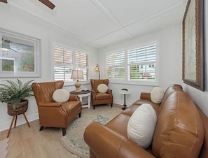 Ein Wohnzimmer mit Ledersofas, einem kleinen Tisch, einer Lampe und einem Blumentopf.