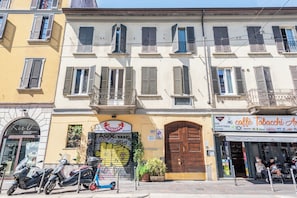 A row of buildings with shuttered windows, a closed wooden door, and a storefront with a sign. - Navigli Garden Terrace - La Vista Apartments (Milano)