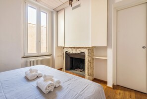 A bedroom with a bed, a fireplace, a radiator, and a window. - Navigli Garden Terrace - La Vista Apartments (Milano)