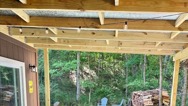 A hot tub with a wooden deck and chairs, surrounded by a forest. - Romantic, peaceful Country getaway. 1-bedroom building with private Hot tub (Nashville)