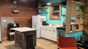 A kitchen with a white refrigerator, a microwave, and a sink. There is a red chair and a blue rug. - Romantic, peaceful Country getaway. 1-bedroom building with private Hot tub (Nashville)