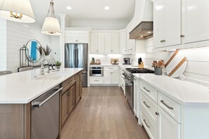 A modern kitchen with white cabinetry, stainless steel appliances, and pendant lighting. -  4 Bedroom- walk to private beach- Tennis-Pickleball- 2 Pools Sleeps 12 (Santa Rosa Beach)