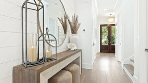 Een hal met een houten console tafel, twee kaarsen, een spiegel en decoratieve vazen.