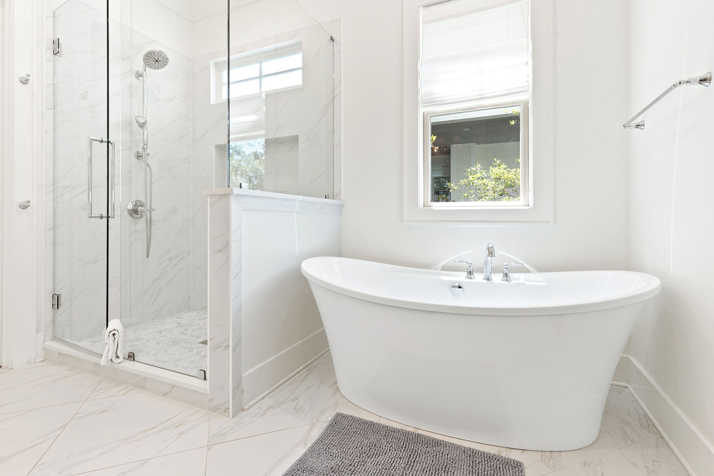 Une salle de bain moderne avec une baignoire sur pieds, une douche à parois de verre et une fenêtre laissant entrer la lumière naturelle.