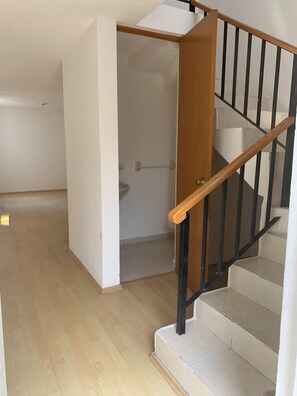Eine Treppe mit hölzernen Geländern und schwarzen Spindeln, die zu einer oberen Etage führt.