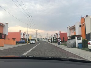 Eine Wohnstraße mit Häusern, ein klarer Himmel und eine Person, die geht.