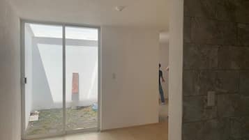 An interior space with a large sliding glass door leading to an outdoor area, a tiled wall, and a wooden floor.