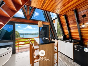 A modern kitchen with a wooden interior, a large window overlooking a lake, and a dining area with a view.