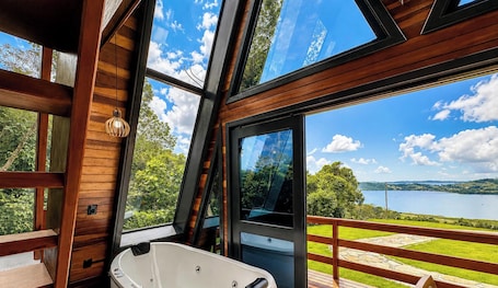 A modern cabin with large windows, a wooden interior, and a view of a lake.. Chalés da Lagoa - Imaruí/SC