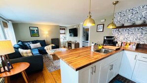 A compact living space with a kitchenette, a sofa, a dining table, and a TV. - Prime Location, Private Rooftop Deck.Walk to Old Port,waterfront, Museums& Music (Portland)