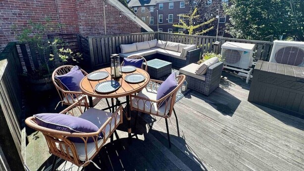 A rooftop patio with a round table, wicker chairs, and a built-in bench. - Prime Location, Private Rooftop Deck.Walk to Old Port,waterfront, Museums& Music (Portland)