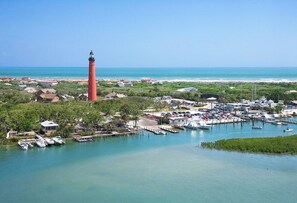 Eine Küstenstadt mit einem markanten roten Leuchtturm, einer Marina mit Booten und Wohnhäusern.