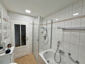 Un baño con bañera, ducha y cabina de ducha de vidrio.