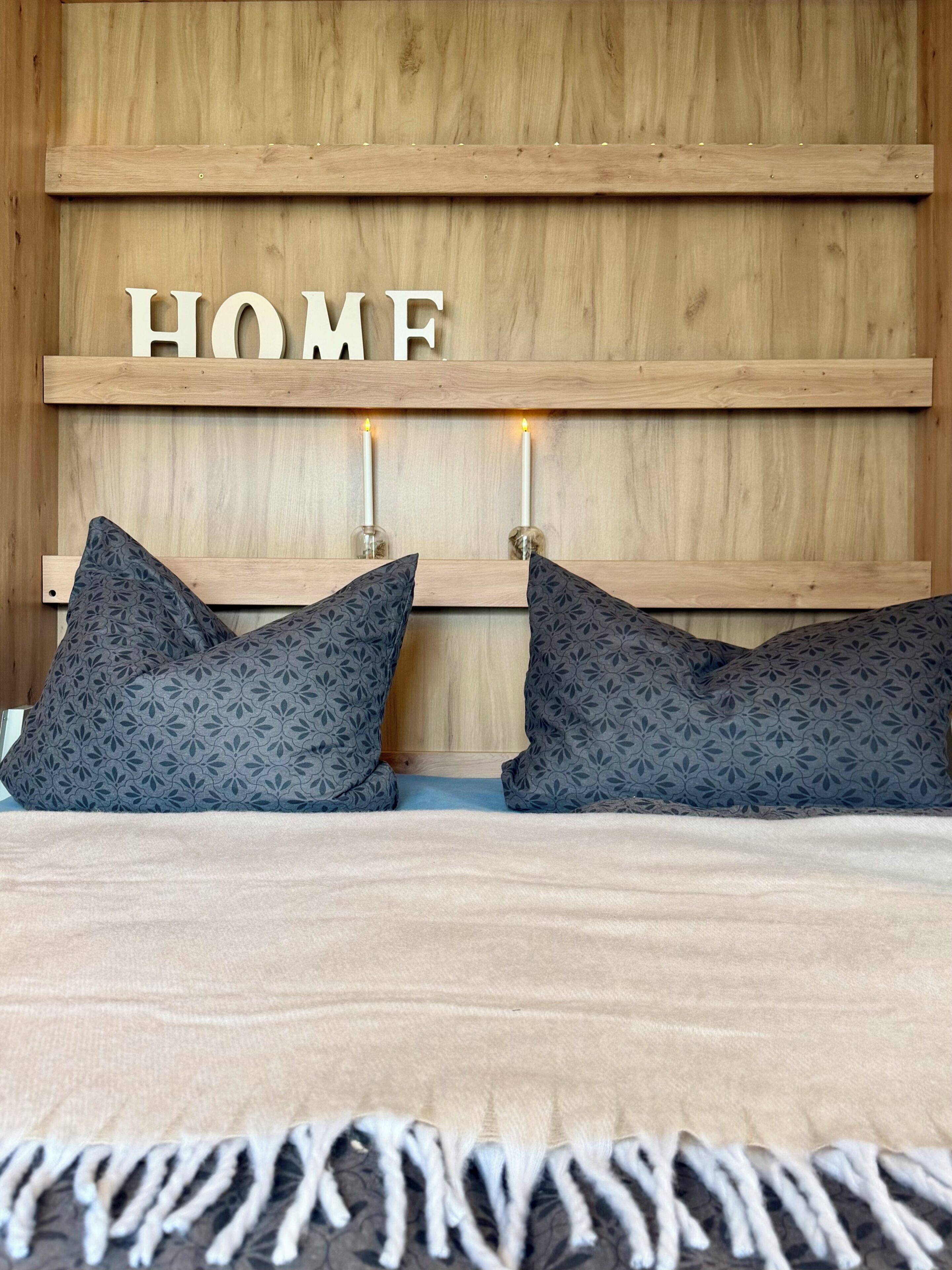 A bed with a wooden headboard, two pillows, and a blanket.