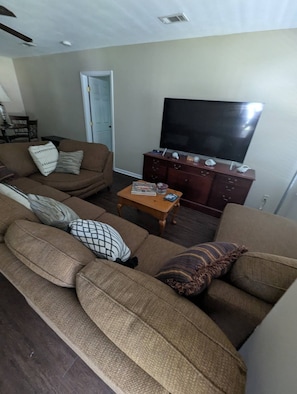 A living room with a sofa set, a coffee table, a flat-screen TV, and a wooden cabinet.