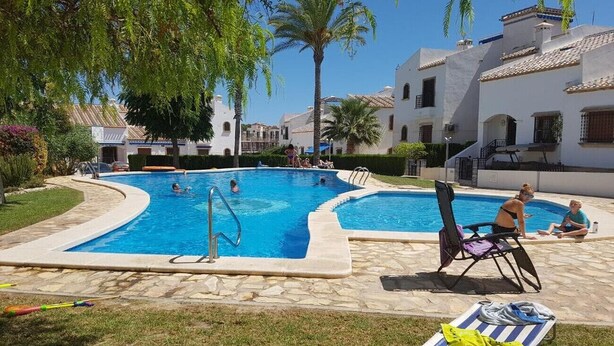 A swimming pool with lounge chairs and palm trees. - Apartment Villamartin (Orihuela Costa)