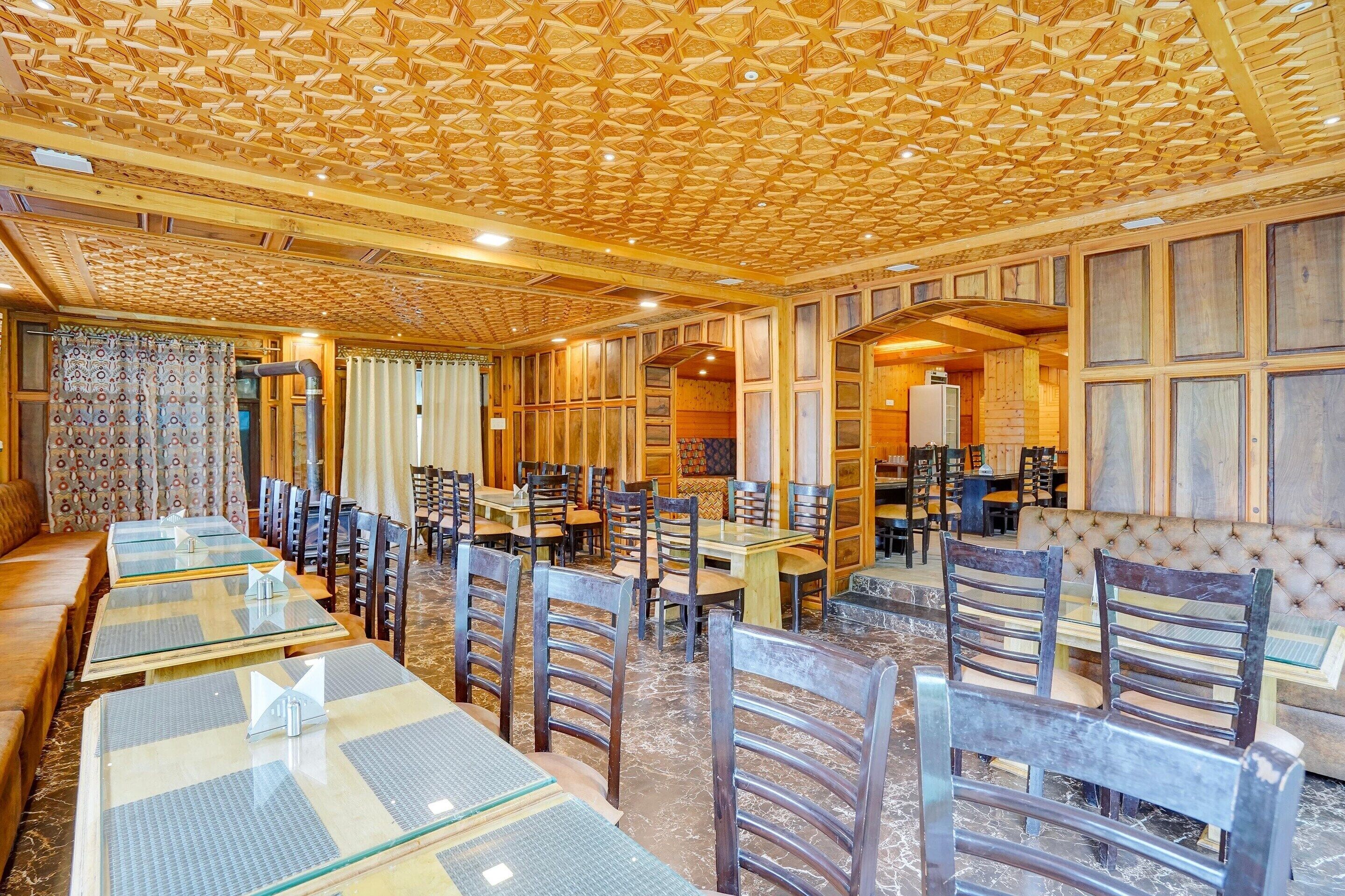 A restaurant with wooden panel walls, a patterned ceiling, and a mix of seating including tables and chairs.