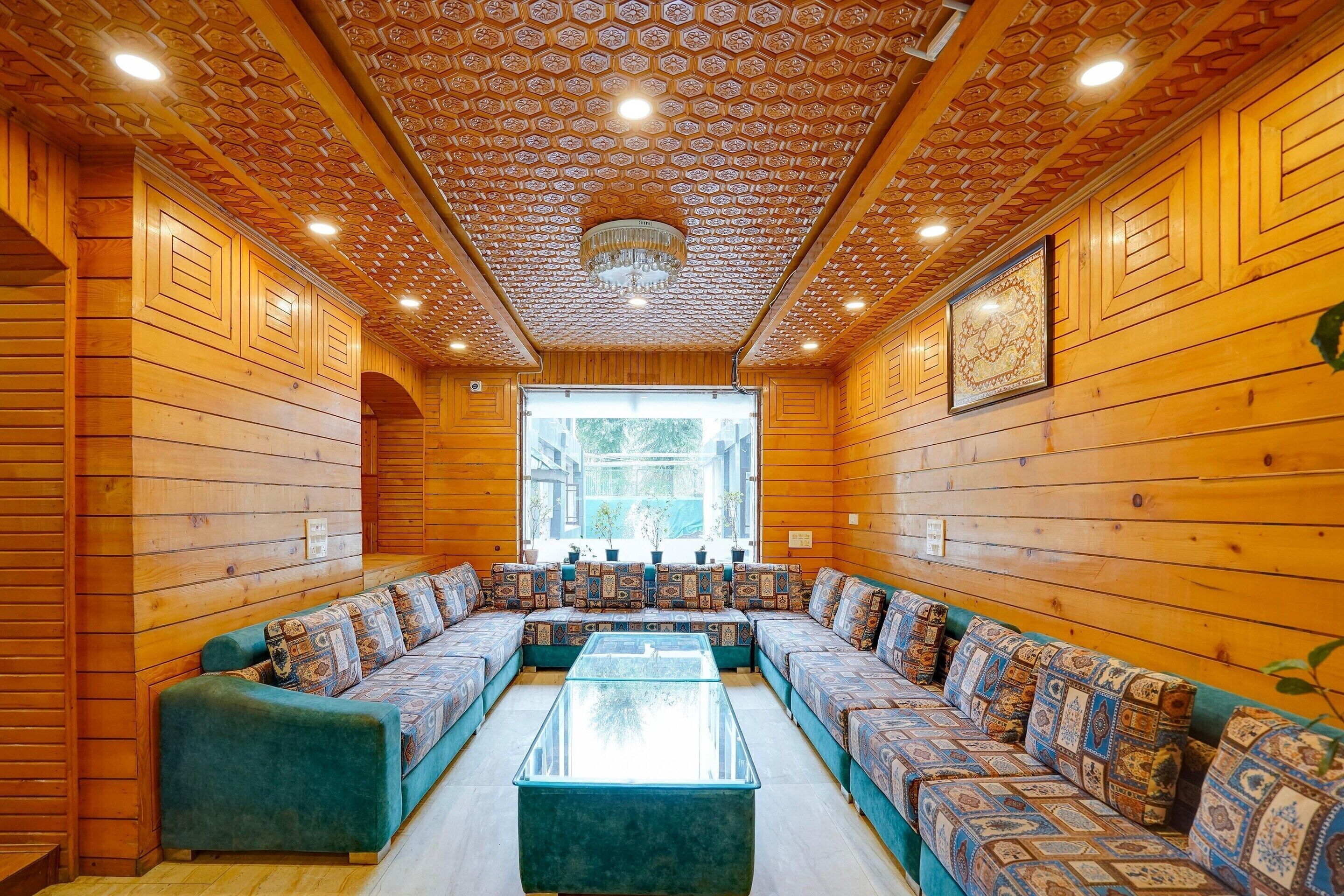 A log cabin interior with a central seating area, wooden walls, and a patterned ceiling.