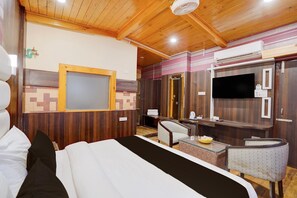 A hotel room with a bed, a desk, a chair, a television, and a mirror. - Saver Double With River View Palette Regency (Anantnag)