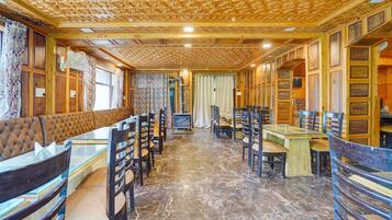 A cozy restaurant with wooden paneling, a fireplace, and a variety of seating options including booths and tables.
