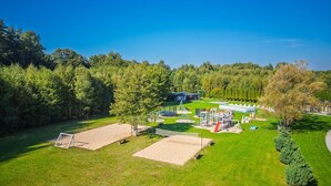 Un parque bien cuidado con una cancha de fútbol, parque infantil y un edificio grande al fondo.