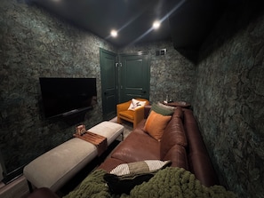 A room with a television, a brown sofa, a small table, and a green door. - Modern & Vintage Vibes, W/ Roof Deck Near Stadiums, Transit & Center City Sites (Philadelphia)