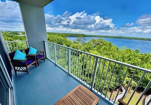 Un balcon donnant sur un lac, entouré de verdure.
