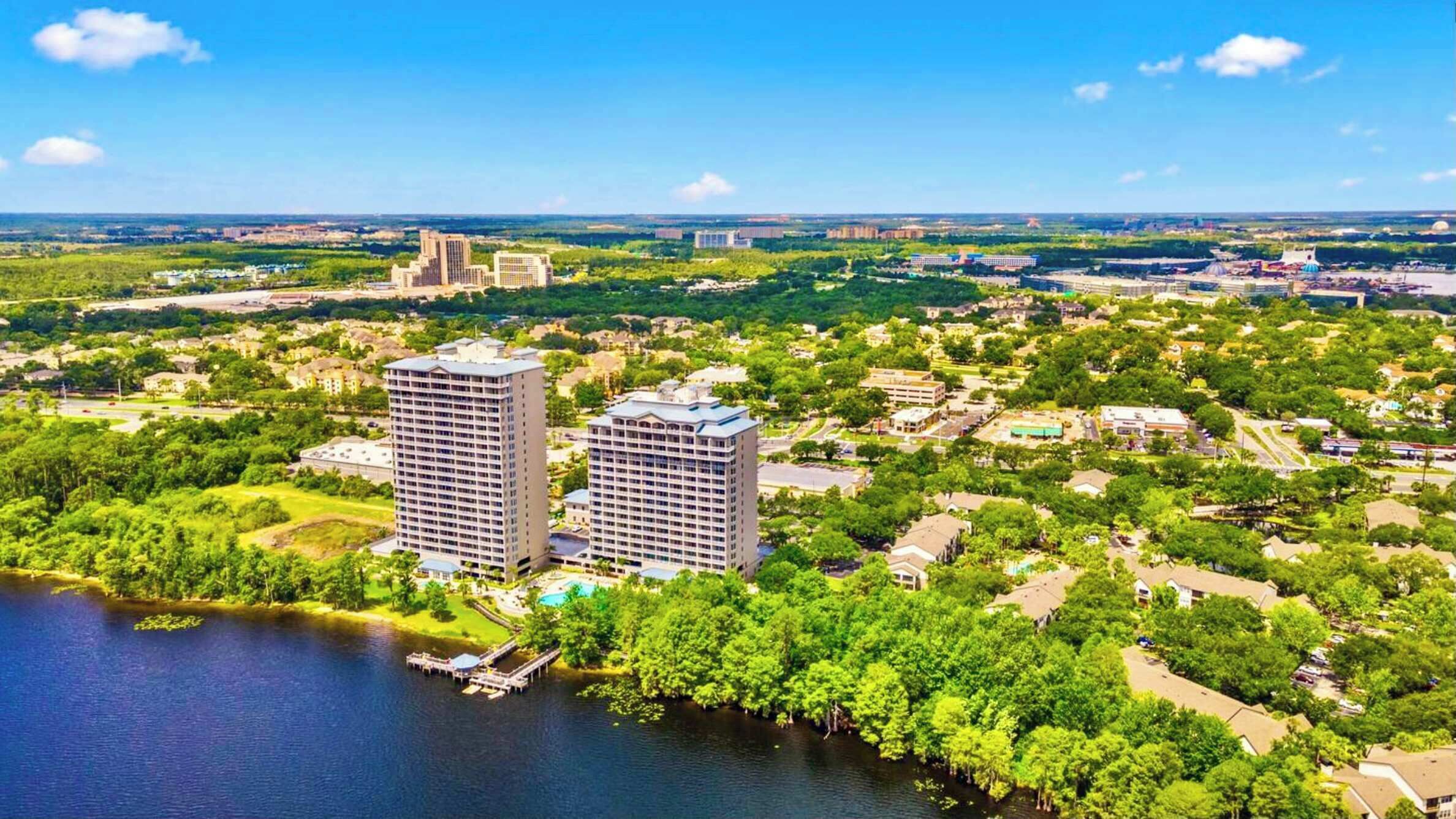 Een hoog hotel met een zwembad, omgeven door weelderige begroeiing en een waterpartij.