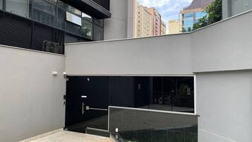 Un edificio moderno con una puerta de entrada negra, un ventanal de vidrio y una barandilla metálica.