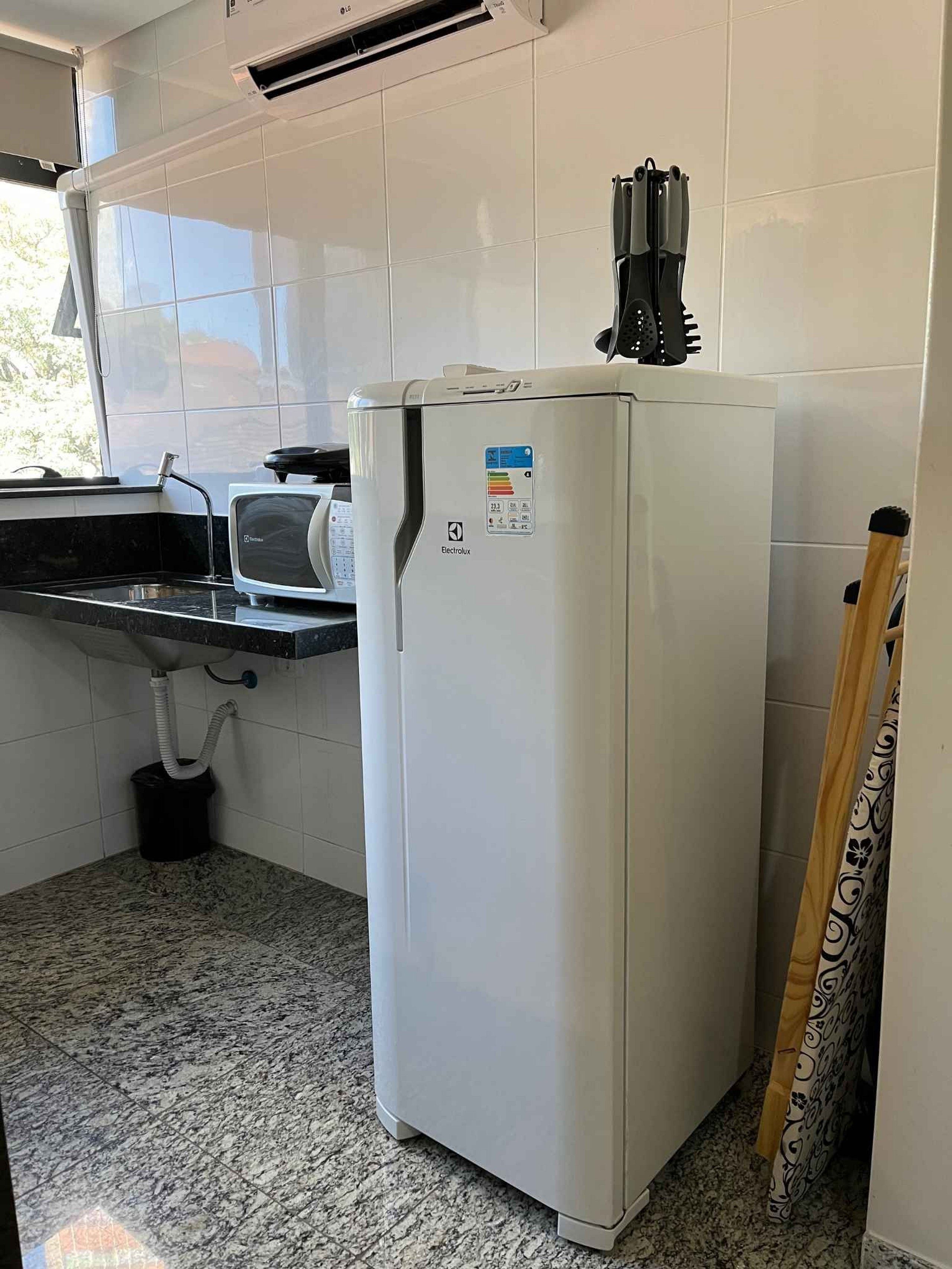 A compact kitchen with a white refrigerator, a sink, and a window.
